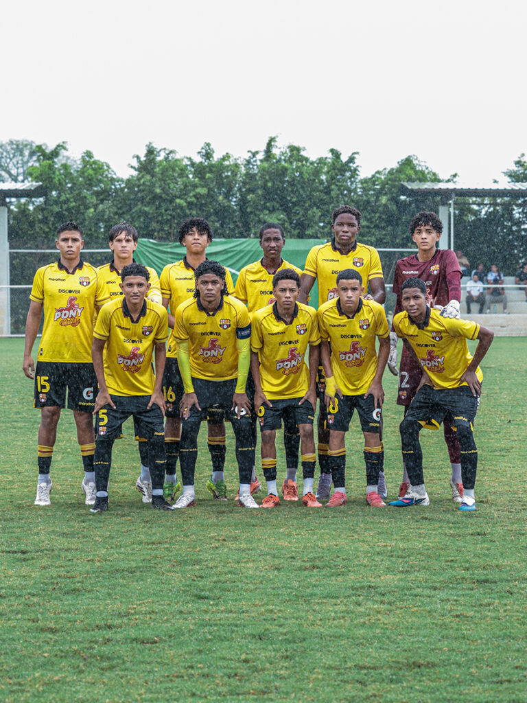 Equipo U15 de Barcelona SC posa en la cancha bajo la lluvia antes de un partido.